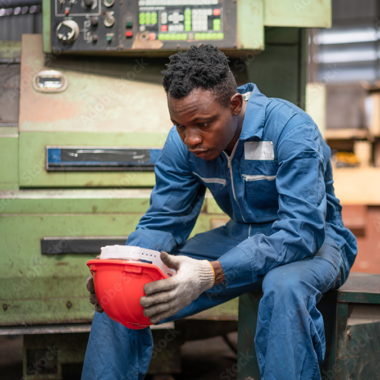 Workshop worker holding a red hard hat