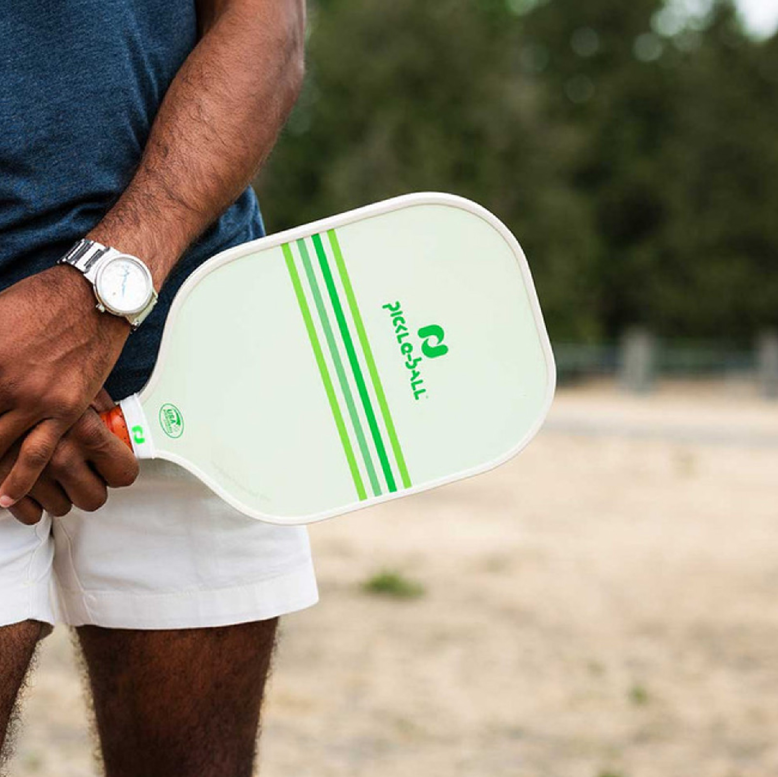 Person holding a green pickleball paddle outdoors
